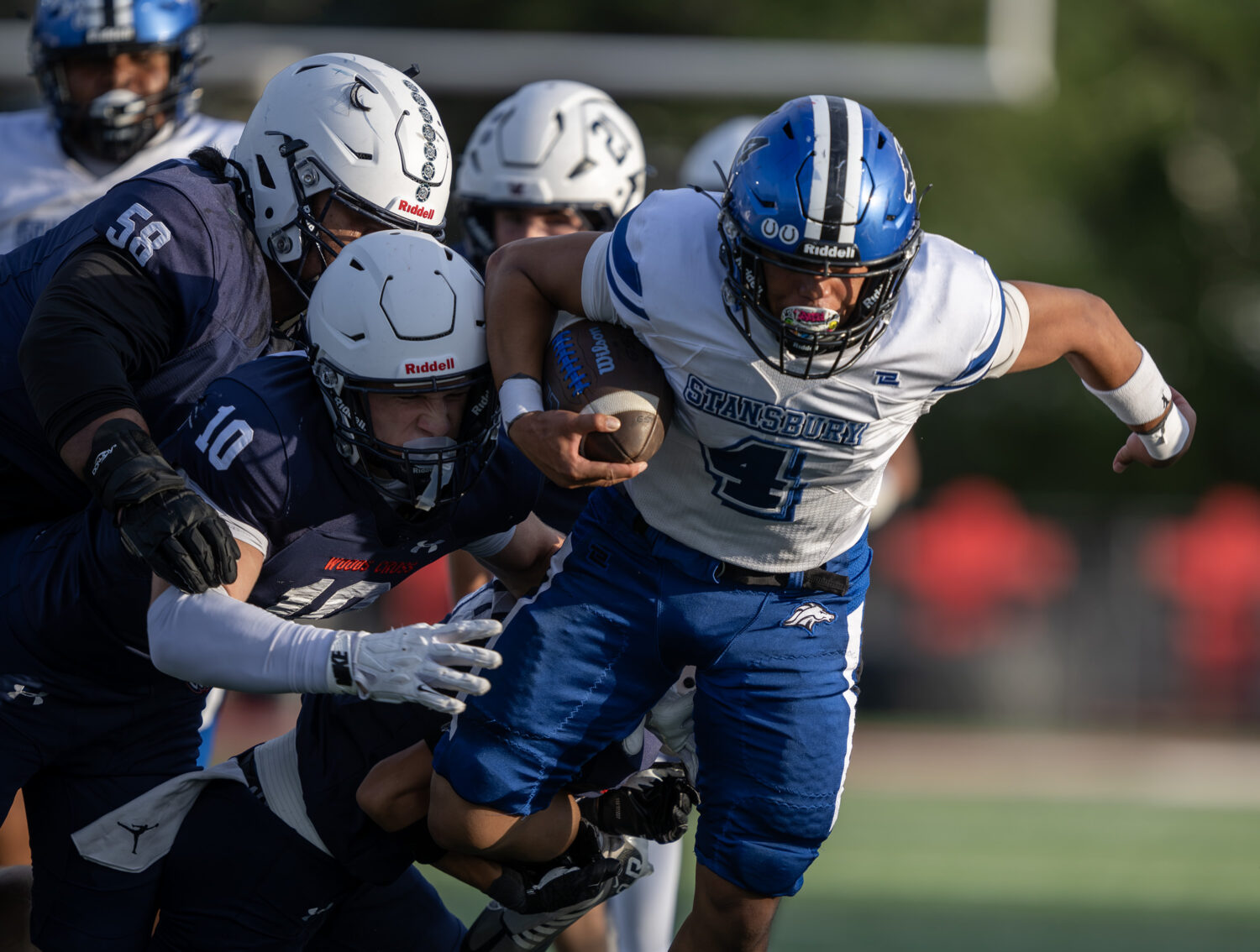 Stansbury’s Robert (Peti) Vaka fights to get away from a group of Woods Cross defenders as they p...