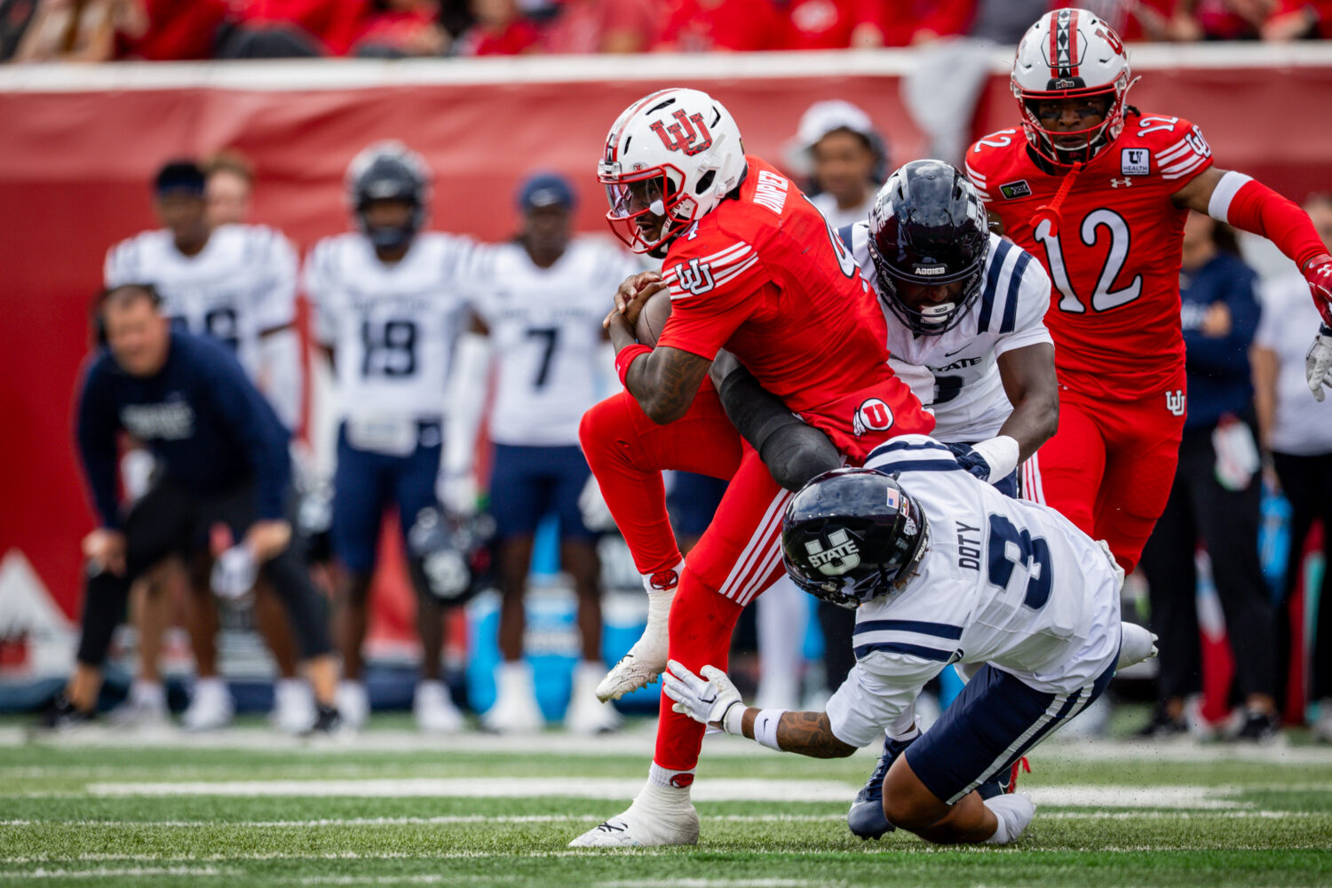 Utah Utes quarterback Devon Dampier (4) is tackled by Utah State Aggies safety Charger Doty (3) dur...